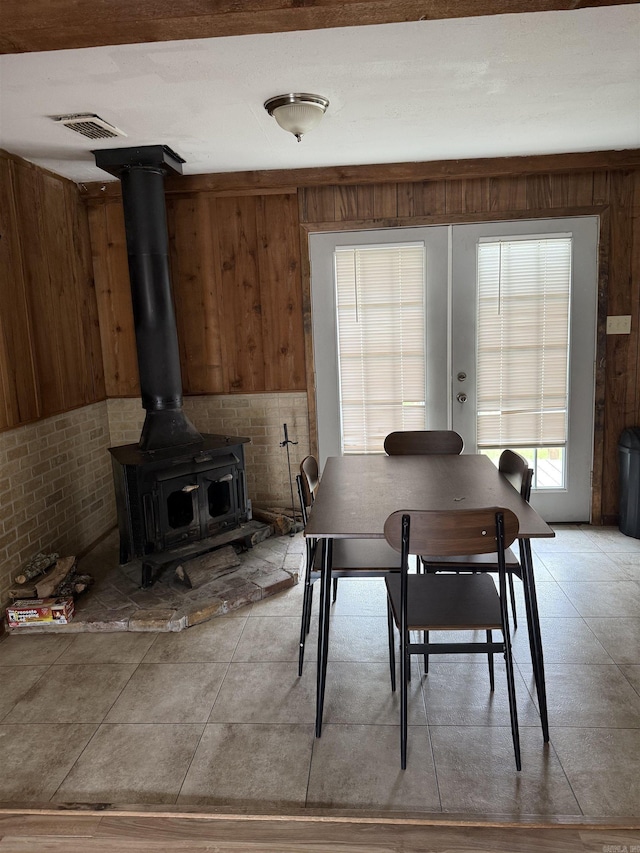 dining area with light tile patterned flooring, a wood stove, and visible vents