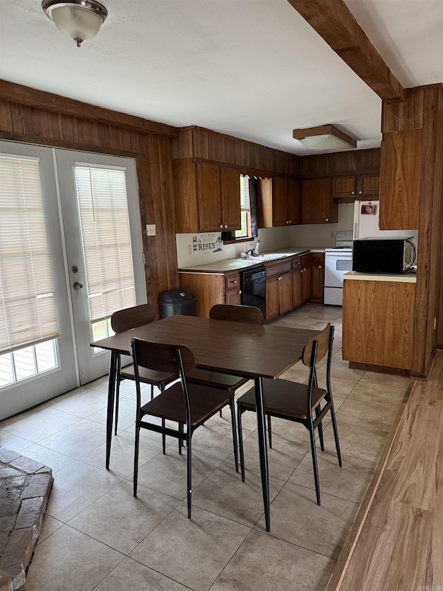 dining area with a healthy amount of sunlight, wood walls, and french doors