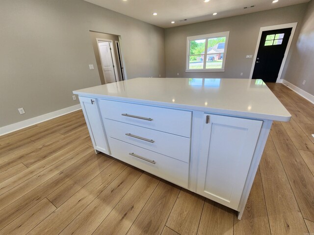 290 Walker St, Higginson, AR 72068 - kitchen with light countertops, light wood-style flooring, a kitchen island, and white cabinetry