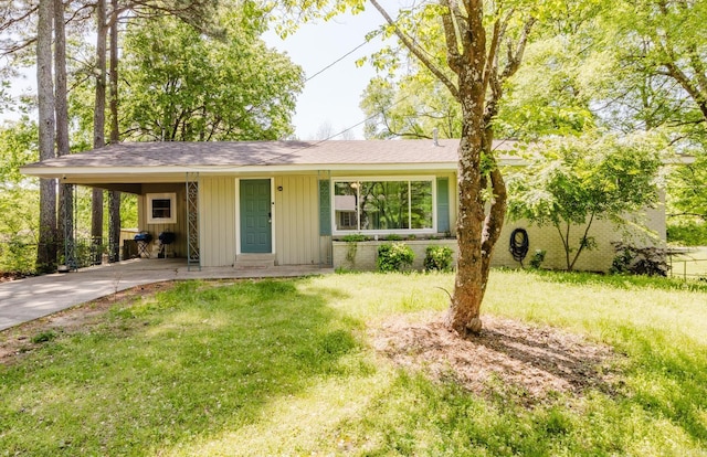 single story home with a carport, a front lawn, driveway, and board and batten siding