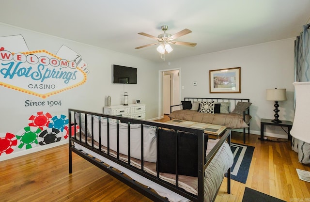 bedroom featuring hardwood / wood-style floors, a ceiling fan, and baseboards