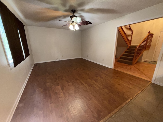 empty room featuring stairs, wood finished floors, a textured ceiling, ceiling fan, and baseboards