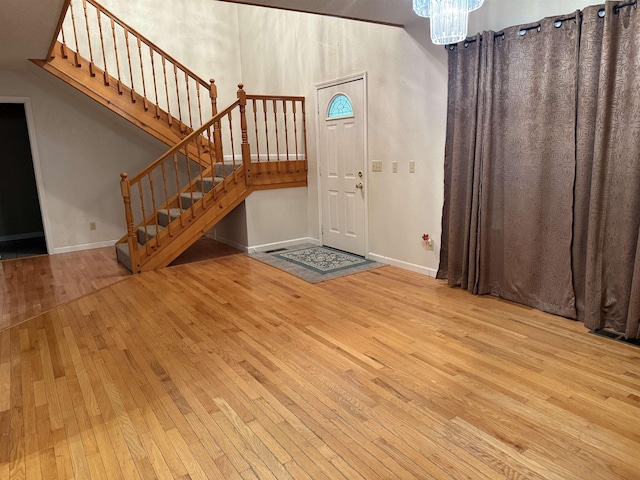 entrance foyer featuring baseboards, a notable chandelier, stairway, and wood-type flooring