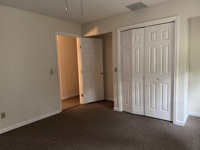 unfurnished bedroom featuring baseboards, visible vents, dark carpet, and a closet