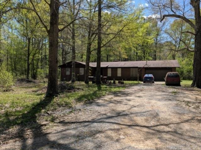 ranch-style home with driveway and a view of trees