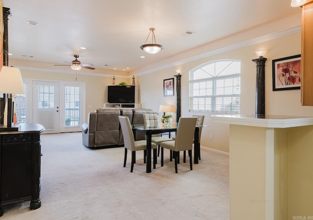 dining area featuring light carpet, baseboards, visible vents, a ceiling fan, and ornamental molding