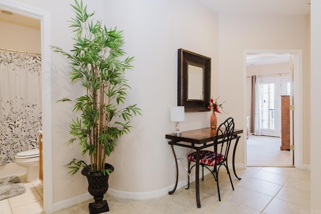 hall featuring baseboards and light tile patterned floors