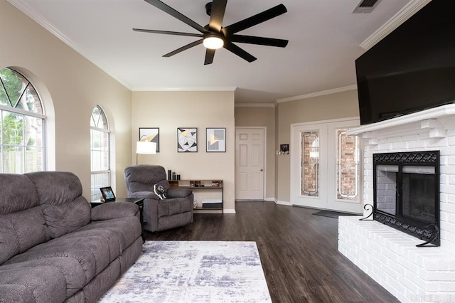 living room featuring dark wood-style floors, baseboards, a ceiling fan, a brick fireplace, and ornamental molding