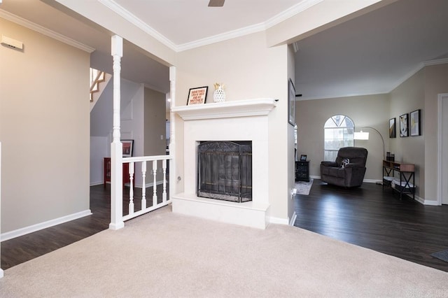 living room featuring baseboards, carpet flooring, a fireplace with raised hearth, and crown molding