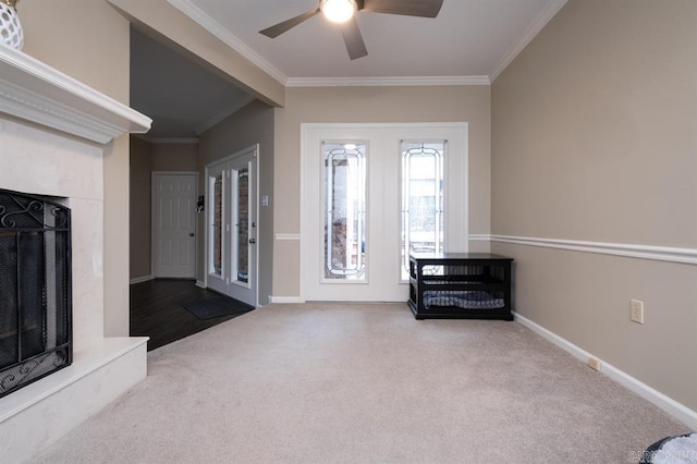 unfurnished living room with a premium fireplace, carpet floors, ceiling fan, and crown molding