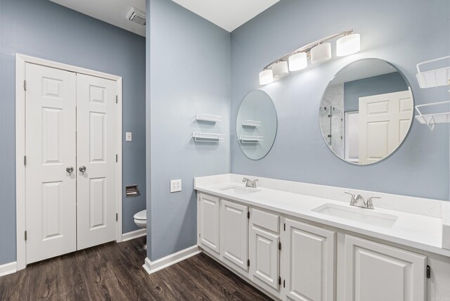 bathroom featuring double vanity, wood finished floors, toilet, and a sink