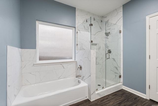 bathroom featuring a shower stall, a garden tub, baseboards, and wood finished floors