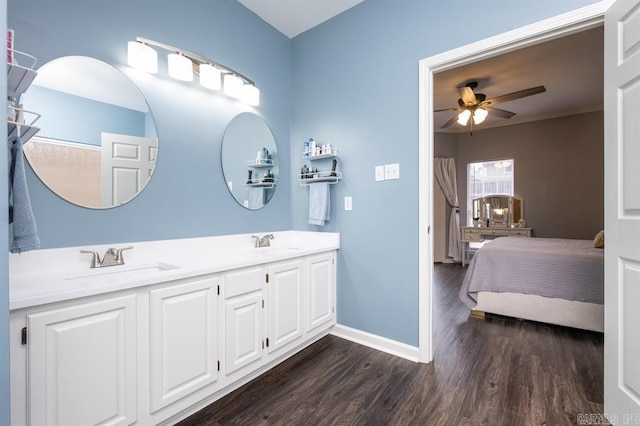 ensuite bathroom featuring ceiling fan, baseboards, wood finished floors, and a sink