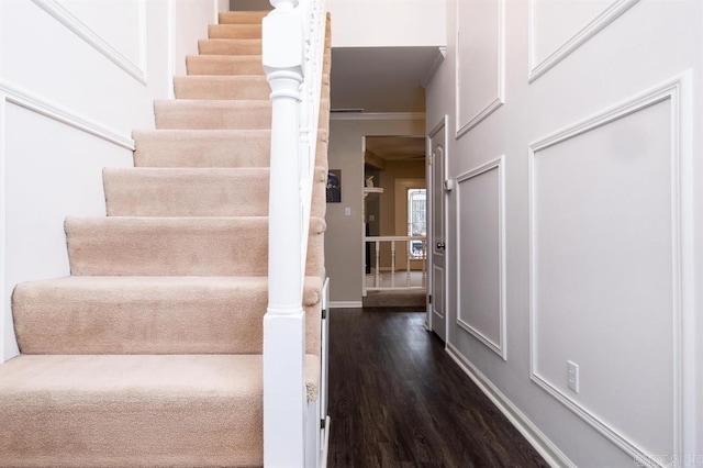 stairs with baseboards, wood finished floors, and ornamental molding