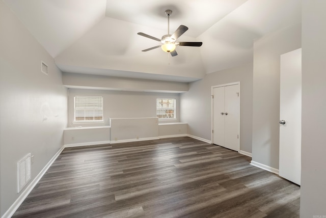 spare room with a ceiling fan, visible vents, vaulted ceiling, and dark wood-style flooring