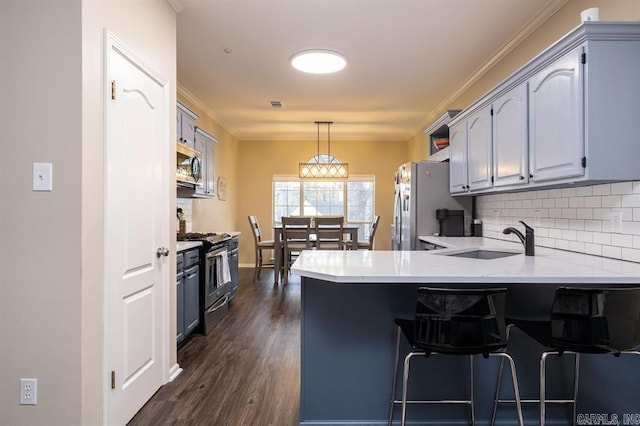 kitchen with a peninsula, a sink, decorative backsplash, light countertops, and appliances with stainless steel finishes