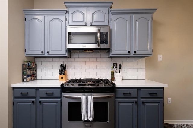 kitchen featuring light countertops, tasteful backsplash, stainless steel appliances, and gray cabinetry
