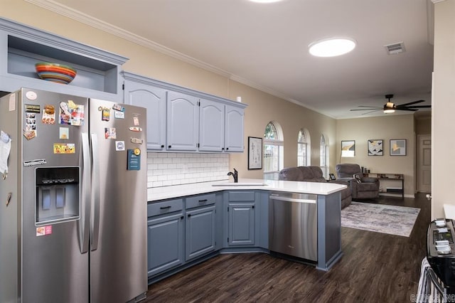 kitchen with stainless steel appliances, a peninsula, a ceiling fan, light countertops, and dark wood-type flooring
