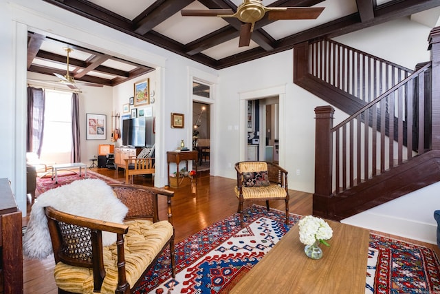 living room featuring ceiling fan, coffered ceiling, wood finished floors, and beamed ceiling
