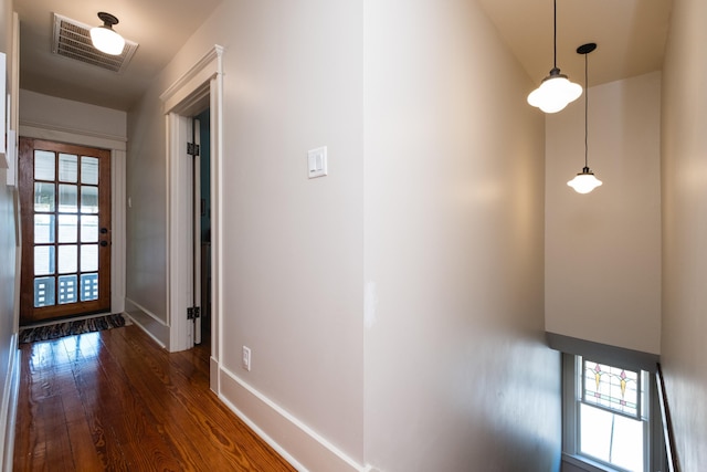 hallway featuring baseboards, visible vents, and dark wood finished floors