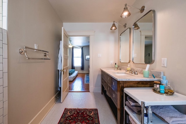 ensuite bathroom featuring ensuite bathroom, baseboards, a sink, and double vanity