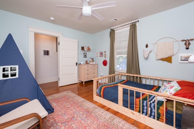 bedroom with visible vents, a ceiling fan, and wood finished floors