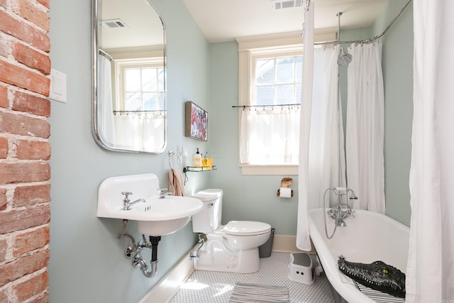 full bath featuring tile patterned floors, a wealth of natural light, toilet, baseboards, and a tub