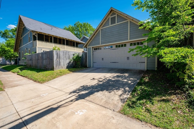 view of side of home with a garage, driveway, fence, and an outdoor structure