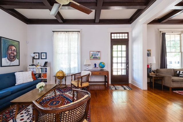 living room featuring baseboards, coffered ceiling, beamed ceiling, ceiling fan, and hardwood / wood-style flooring