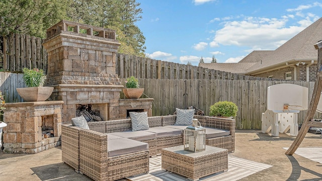 view of patio / terrace with a fenced backyard and an outdoor living space with a fireplace