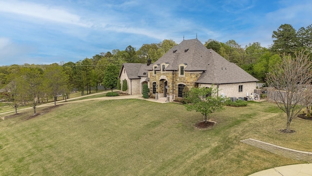 exterior space featuring stone siding, a front yard, and concrete driveway