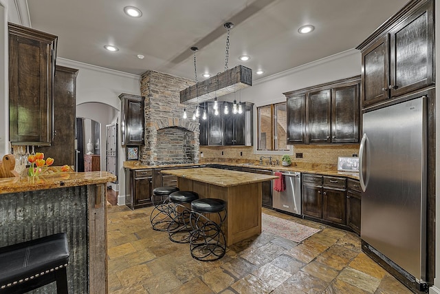 kitchen with crown molding, a breakfast bar area, arched walkways, stainless steel appliances, and backsplash
