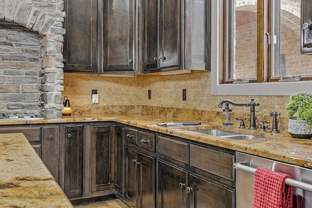 kitchen with tasteful backsplash, appliances with stainless steel finishes, light stone counters, and a sink