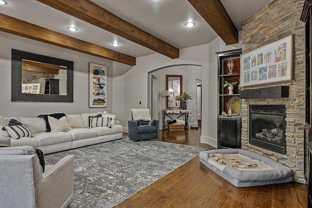 living area with baseboards, arched walkways, wood finished floors, and a fireplace