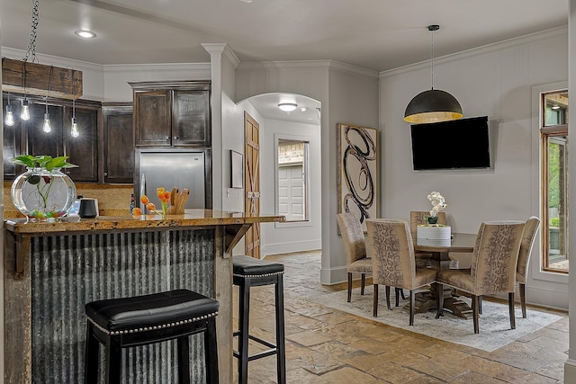 dining room featuring baseboards, stone tile flooring, arched walkways, and crown molding