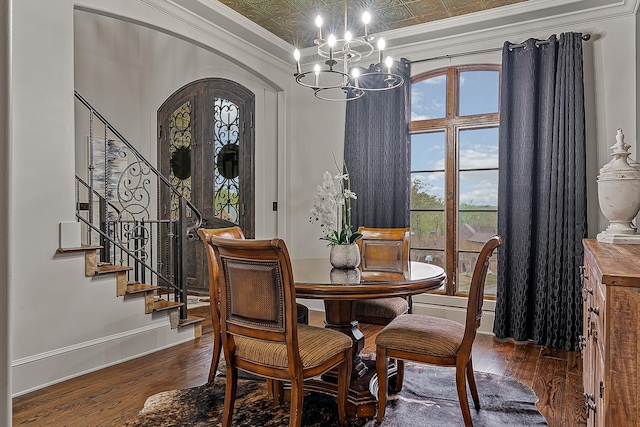 dining area with an inviting chandelier, arched walkways, crown molding, hardwood / wood-style flooring, and stairs