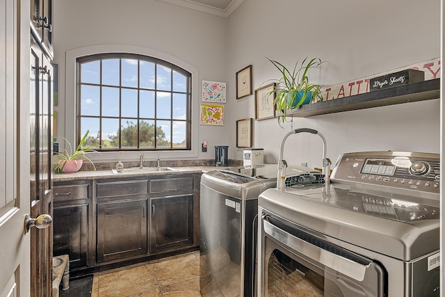 washroom featuring crown molding, washer and clothes dryer, a sink, and cabinet space