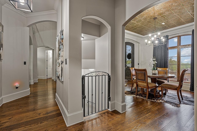 interior space with arched walkways, crown molding, dark wood-style flooring, and an inviting chandelier