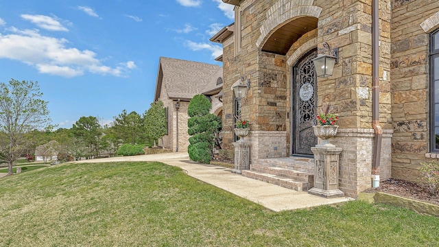 doorway to property with a lawn and stone siding
