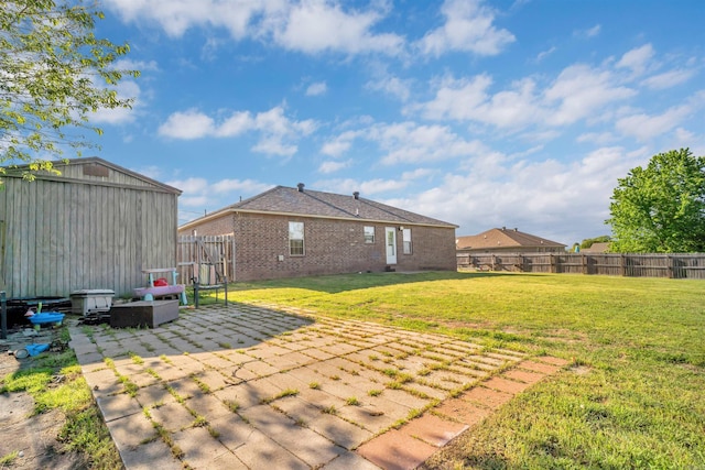 view of yard with a patio area, a fenced backyard, and an outdoor structure