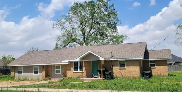ranch-style home with fence, a shingled roof, and brick siding