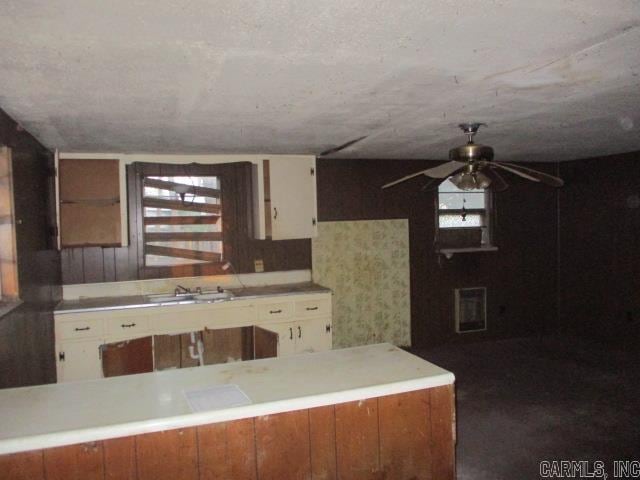 kitchen featuring light countertops, a ceiling fan, white cabinetry, and a sink
