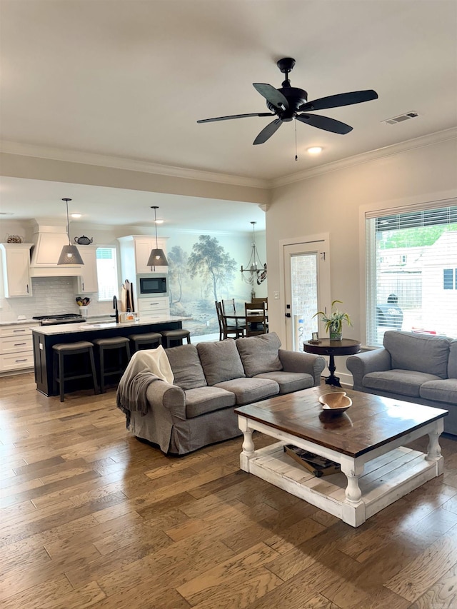 living area with hardwood / wood-style floors, visible vents, crown molding, and plenty of natural light