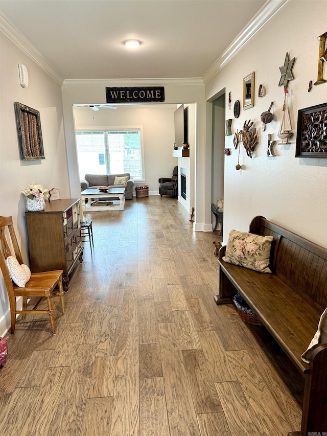 corridor featuring wood finished floors, crown molding, and baseboards