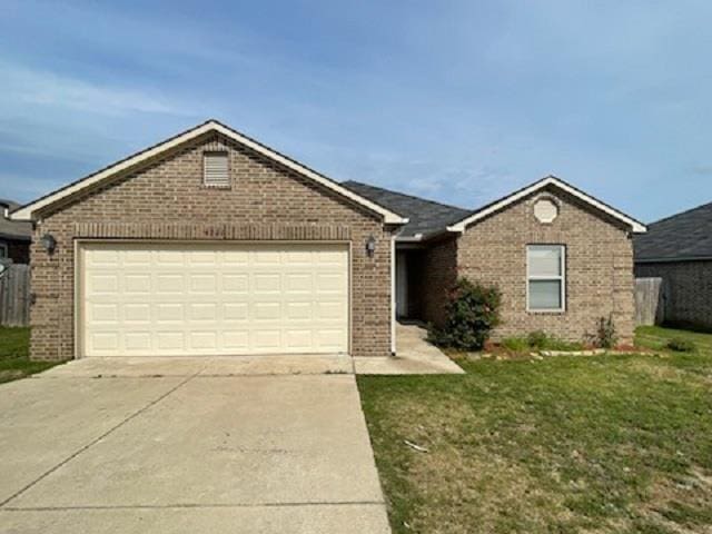 ranch-style house featuring brick siding, an attached garage, driveway, and a front yard