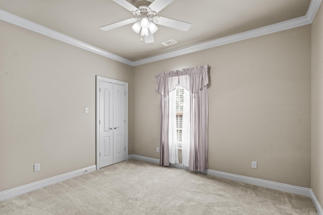 empty room featuring baseboards, visible vents, ceiling fan, carpet floors, and ornamental molding