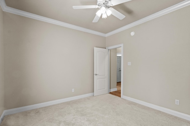 carpeted spare room with baseboards, ceiling fan, and crown molding