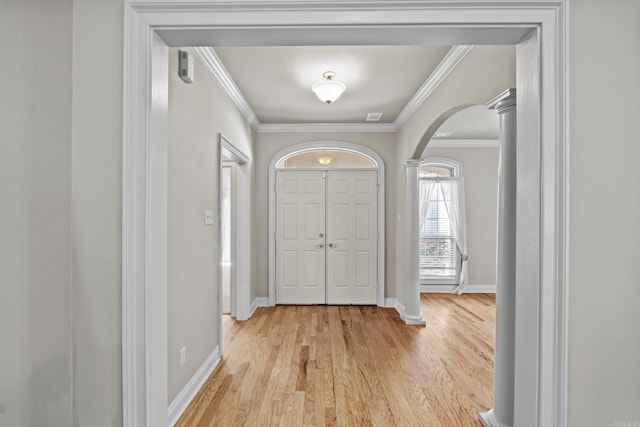 entryway with arched walkways, light wood-type flooring, crown molding, and baseboards