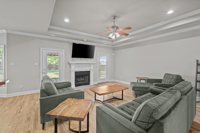 living area with a tray ceiling, baseboards, and ceiling fan