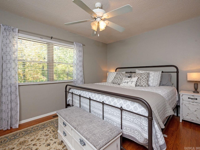 bedroom featuring ceiling fan, baseboards, wood finished floors, and a textured ceiling